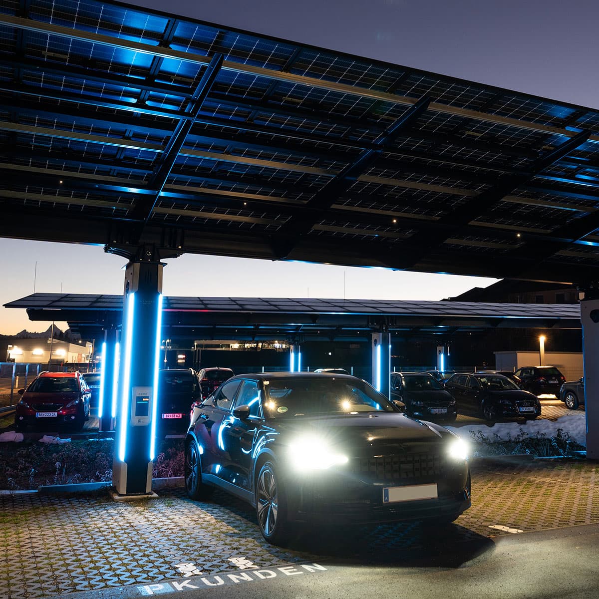 Elektrofahrzeuge unter beleuchtetem Solarcarport in der Nacht